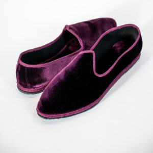 This velvet slipper embodies the sophistication of classic eveningwear. Crafted from luxurious velvet in a rich burgundy hue, it features a sleek, streamlined silhouette enhanced by tone-on-tone piping that highlights its refined character. Designed for special occasions and formal settings, it combines comfort and elegance in a timeless style statement.
